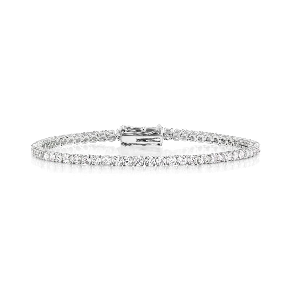 The Round Brilliant Diamond Tennis Bracelet features a continuous row of round diamonds set in delicate 18K white gold, secured with a clasp and shown on a plain white background.