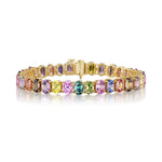 The Multicolor Oval Sapphire Tennis Bracelet showcases purple, pink, yellow, green, and blue sapphires set in 18K yellow gold in an elegant continuous design.
