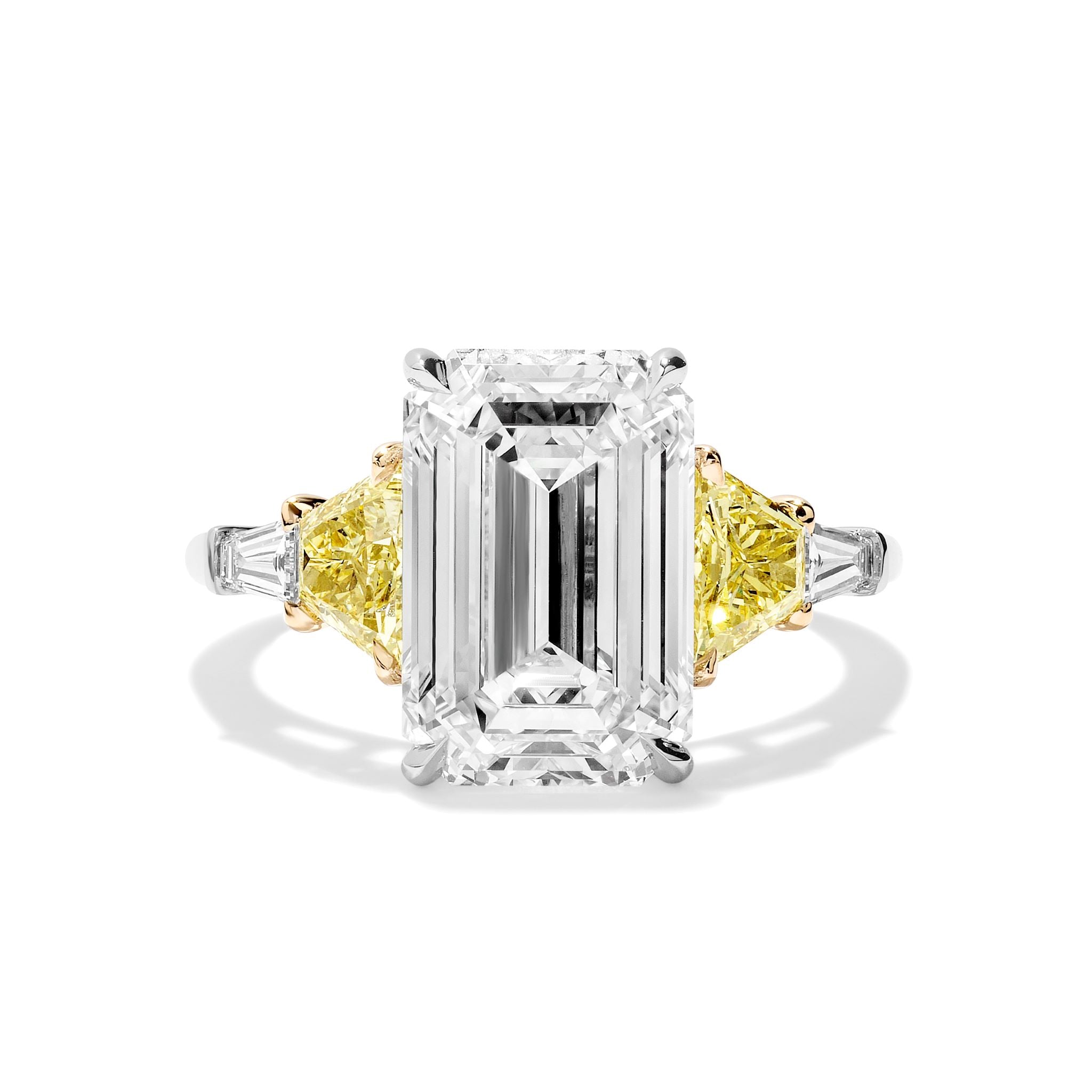 The Emerald Cut Diamond Engagement Ring features a striking emerald-cut center, fancy yellow trapezoid, and white tapered baguette side stones—set in white and yellow metal for a perfect symbol of life’s special moments.