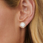 A close-up of a woman's ear wearing Pavé Octagon Ear Jackets with round brilliant diamonds in 18k gold; the large center stone is surrounded by a halo of smaller diamonds, and her blonde hair is partially visible.