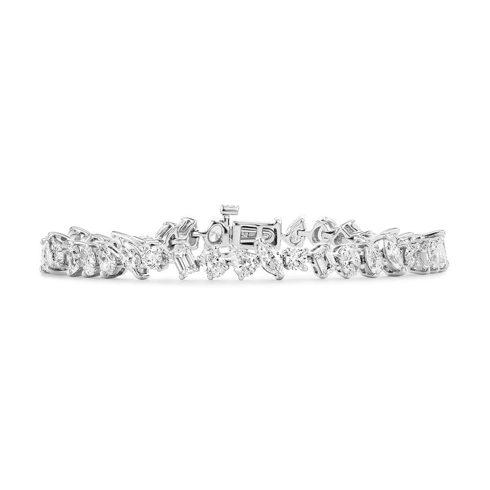 The Mixed Shape Diamond Tennis Bracelet showcases various diamond shapes in a continuous row with a silver clasp, elegantly displayed against a white background.