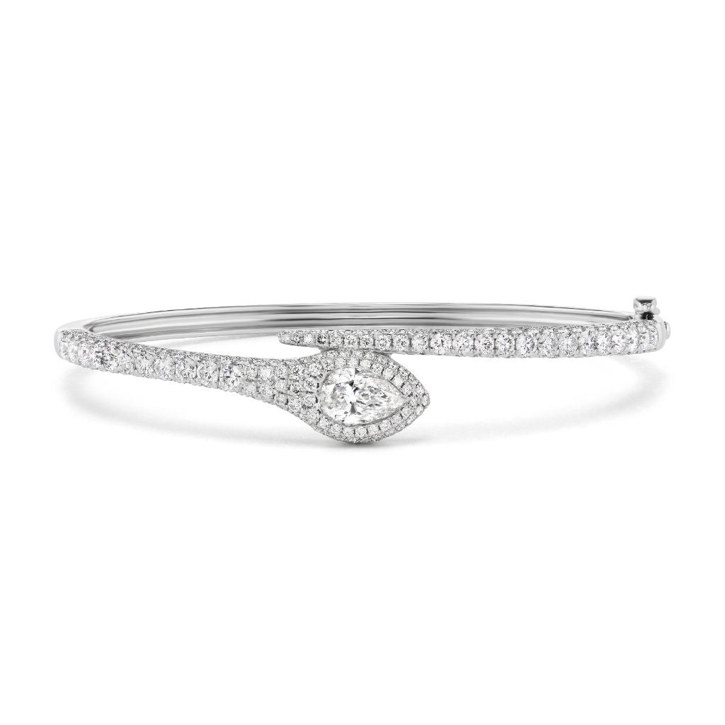 The Pavé Serpent Diamond Bangle is a silver snake-inspired bracelet adorned with small diamonds and features a teardrop-shaped centerpiece with a larger central diamond encircled by smaller stones.
