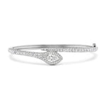 The Pavé Serpent Diamond Bangle is a silver snake-inspired bracelet adorned with small diamonds and features a teardrop-shaped centerpiece with a larger central diamond encircled by smaller stones.