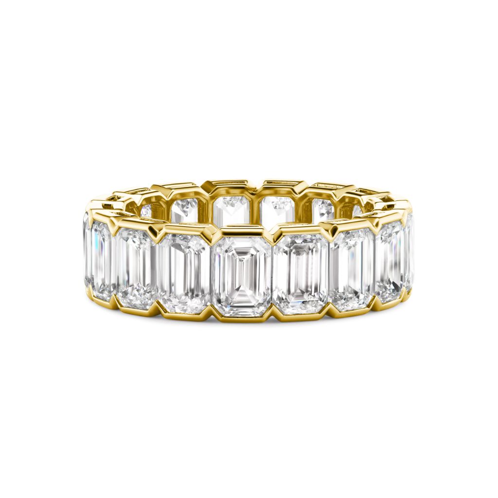 The Half Bezel Emerald Cut Diamond Eternity Band showcases large emerald-cut diamonds encircling the gold band, displayed on a white background.