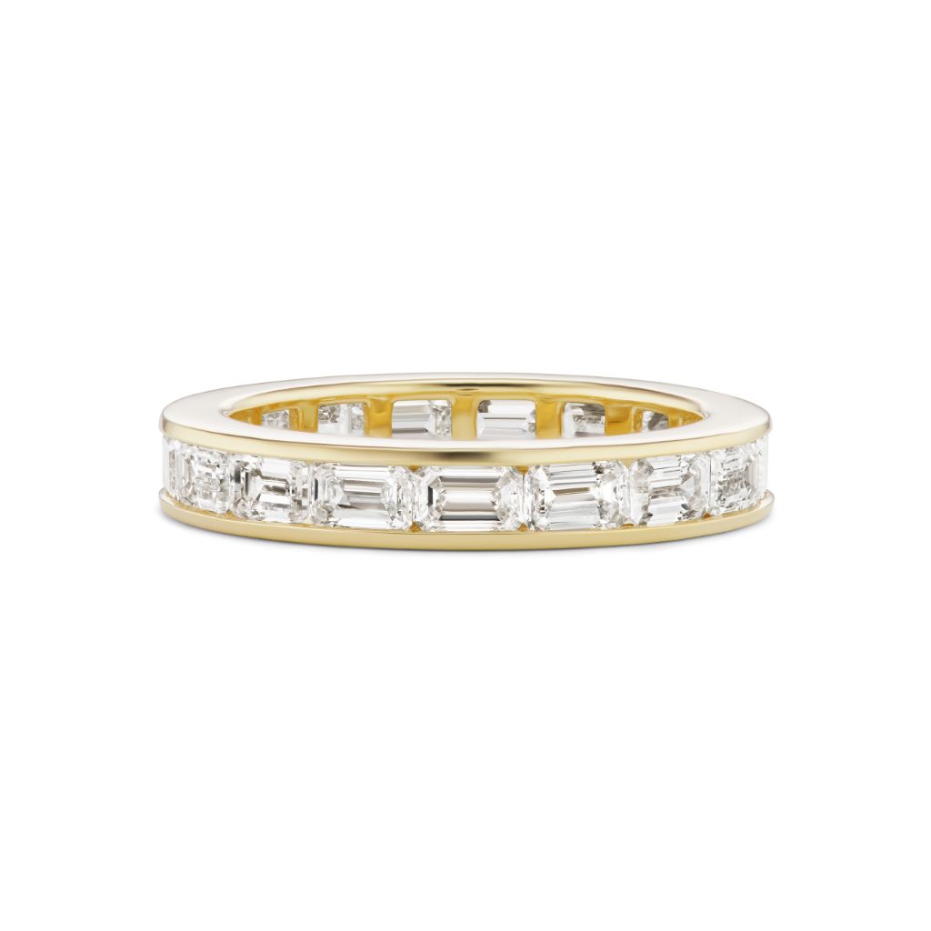 The Emerald Cut Diamond Channel Set Eternity Band showcases rectangular and square emerald-cut diamonds encircling the band, with open side details—an ideal choice for a custom celebration or bridal eternity ring.