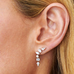 Close-up of a woman's ear adorned with Mixed Shape Waterfall Earrings featuring round, rectangular, marquise-cut, and kite VS+ diamonds set in 18K white gold. Blonde hair softly frames her ear.